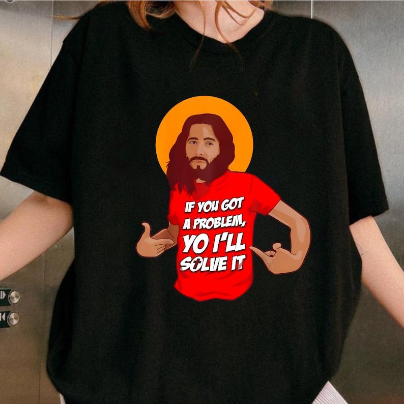 A person wearing a black t-shirt with a graphic design depicting a man with a beard and long hair, along with text that reads "If you got a problem, you'll solve it".