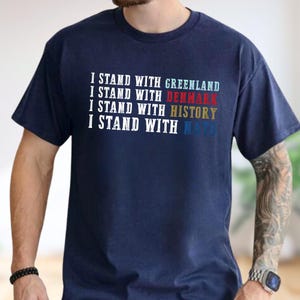 A man wearing a navy blue t-shirt with text printed on it.