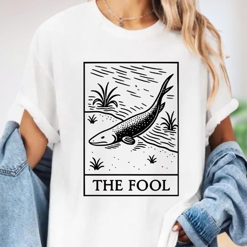 A white t-shirt with a graphic design depicting a fish and the text "THE FOL" printed on it.