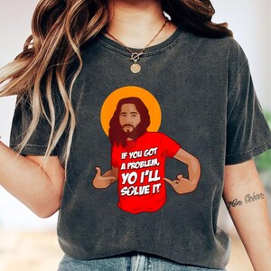 A person wearing a gray t-shirt with a graphic design depicting a man with a beard and the text "If you got a problem, you'll solve it" printed on it.