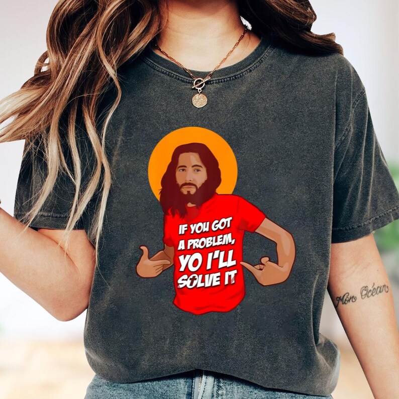A person wearing a gray t-shirt with a graphic design depicting a man with a beard and the text "If you got a problem, you'll solve it" printed on it.