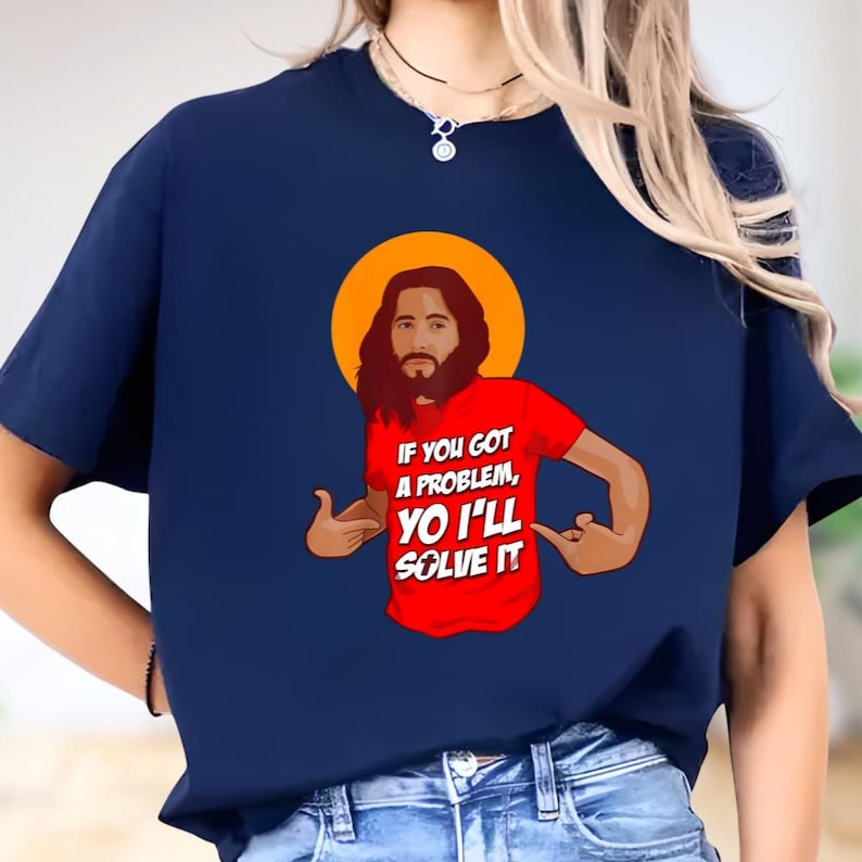 A person wearing a blue t-shirt with a graphic design depicting a man with a beard and the text "If you got a problem, you'll solve it" printed on it.