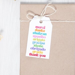 May include: A white gift tag with the words "merci", "danke", "shukran", "spasibo", "arigato", "gracias", "xiexie", "obrigado", "grazie", and "thank you" written in different colors.