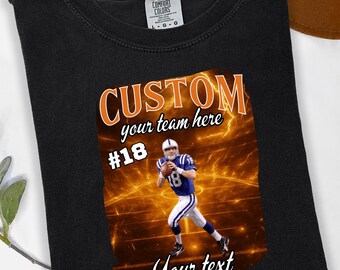 Pode incluir: Camiseta preta com um gráfico de jogador de futebol americano. O gráfico apresenta um jogador de futebol americano em uniforme azul e branco com o texto "CUSTOM your team here #18 Your text". A camisa tem o texto "DTF TRANSFER" na parte superior e inferior.