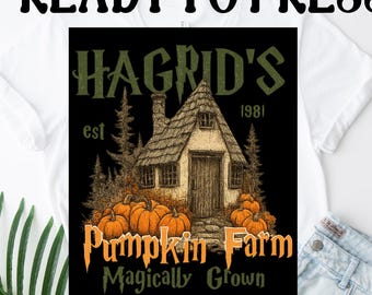 May include: White t-shirt with a black graphic featuring a cottage, pumpkins, and the text "Hagrid's Pumpkin Farm" and "Magically Grown." The words "Ready to Press" and "DTF Transfers" are also printed on the shirt.