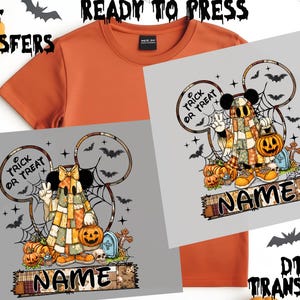May include: Orange t-shirt with a Halloween-themed graphic. The graphic features a cartoon character in a patchwork costume, holding a jack-o'-lantern, with the text "TRICK OR TREAT" and "NAME". Bats and spiderwebs are also included in the design. The words "DTF TRANSFERS" and "READY TO PRESS" are also visible.