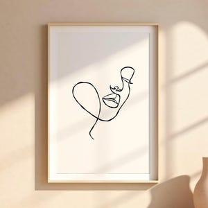 May include: A black and white line drawing of a face with a single continuous line. The drawing is framed and hanging on a wall.