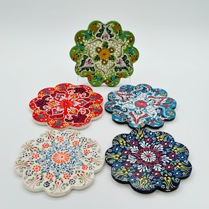 Puede incluir: Conjunto de cinco posavasos de cerámica con intrincados diseños florales en tonos rojos, verdes, azules y blancos. Los posavasos tienen un borde festoneado y son perfectos para proteger las superficies del calor.