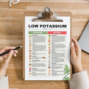May include: A clipboard with a printed "Low Potassium Food List" in black and green. The list categorizes foods to choose and avoid, with sections for vegetables, fruits, grains, proteins, dairy, nuts, beverages, sweets, and condiments. A hand holds a pencil.