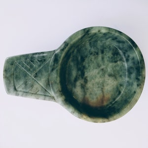 Peut inclure: Une coupe à boire en pierre verte et brune avec une anse. La coupe est faite d'une pierre lisse et polie et a un aspect marbré.