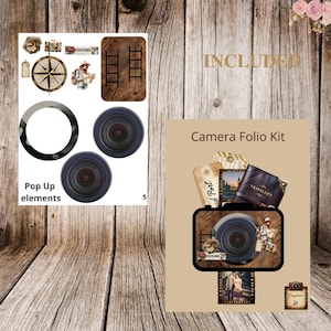 May include: A Camera Folio Kit with pop-up elements. The kit features a camera-shaped design with a lens, a compass, a suitcase, and a traveler illustration. The kit has a vintage, travel-themed aesthetic.