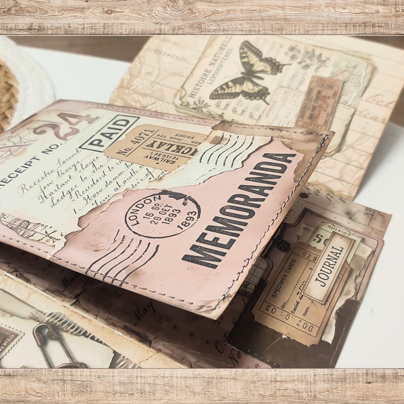 May include: A handmade paper journal featuring a collage of vintage-style ephemera, including a "MEMORANDA" stamp, a London postmark dated 1893, a "PAID" receipt, and a butterfly illustration. The cover has stitched edges and aged paper textures.