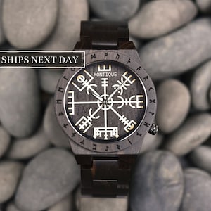 Puede incluir: Un reloj de pulsera de madera marrón oscuro con una esfera negra y detalles dorados. La esfera presenta un diseño de brújula con runas alrededor del borde. La correa del reloj es de madera y tiene un acabado marrón oscuro. La esfera del reloj dice "Montique".