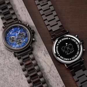 May include: Two dark wood and metal watches. One watch has a blue face with multiple dials and the word "PROFIQUE". The other watch has a black face with the words "TO MY HUSBAND, I LOVED YOU THEN, I LOVE YOU STILL, ALWAYS WILL, ALWAYS HAVE, Love Forever".