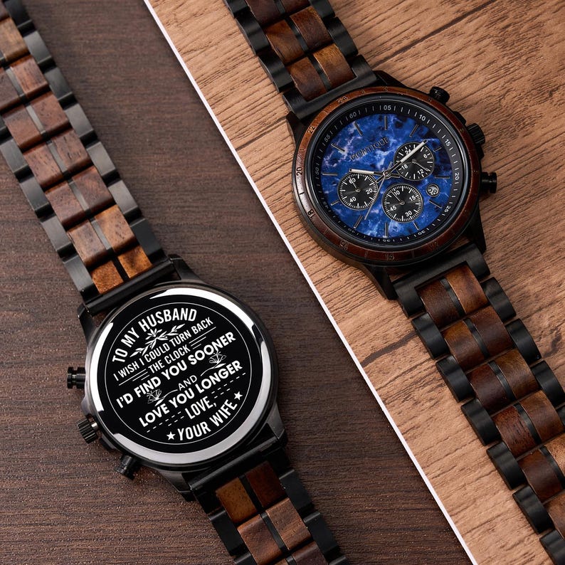 May include: Two wooden watches with black metal accents. One watch has a blue face with subdials, the other has a white face with text that reads "To my husband...I'd find you sooner...Love, your wife."