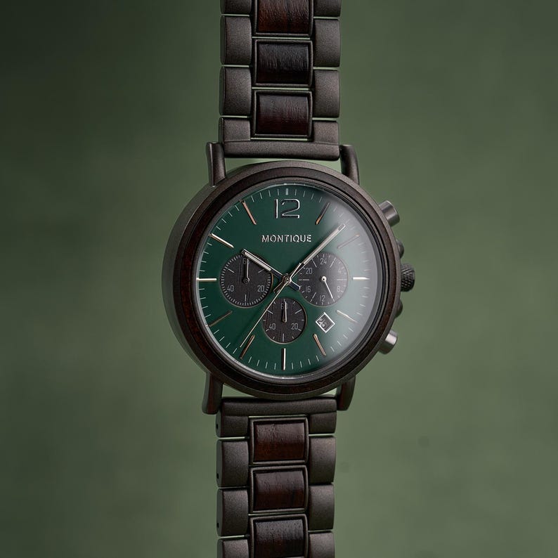 Puede incluir: Un reloj de pulsera de madera oscura y metal con esfera verde. El reloj muestra la palabra "MONTIQUE" y tiene tres subesferas. La correa del reloj est&aacute; hecha de eslabones de madera oscura y metal. El fondo es verde.