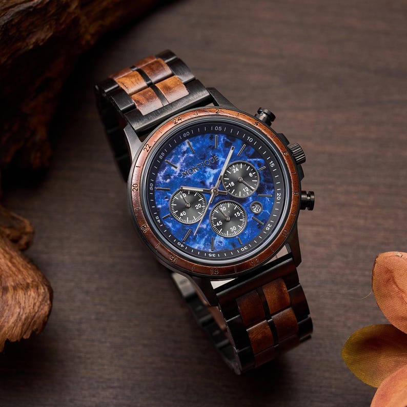 May include: A wristwatch with a blue marble-effect face and a wooden bezel and band. The watch face has multiple sub-dials and the brand name "MONTIQUE". The watch is set against a dark wood background.