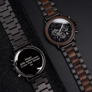 May include: Two black wooden watches with chronograph dials. One watch has a message engraved on the face that reads, "Happy 30th Anniversary. I Love You Always xo." The other watch has a wooden bezel and a black face with white hands.
