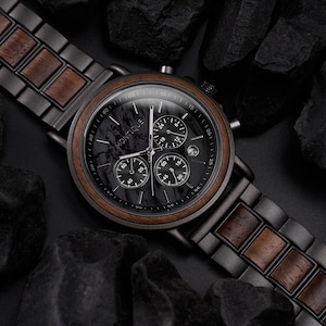 May include: A black and brown Montique chronograph watch with a black marble-style face and wooden bezel. The watch has three sub-dials and a date window. The watch band is black metal with wooden accents.