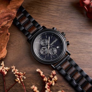 May include: A black Montique chronograph watch with a dark blue face and a wooden band. The watch features three sub-dials and a date display. The band combines black metal links with wooden inserts, set against a wooden surface.