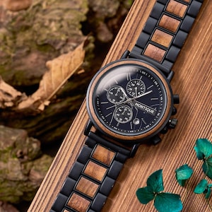 May include: A black wristwatch with a wooden bezel and band links. The watch face is dark blue with three sub-dials and the word "MONTIQUE" printed in white. The watch is displayed on a wooden surface.