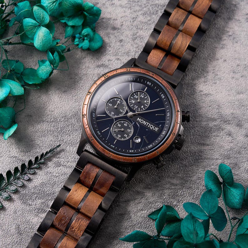 Op de afbeelding: Een zwart polshorloge met een donkerblauwe wijzerplaat en drie sub-wijzerplaten. Het horloge heeft een houten en zwartmetalen band. Op de wijzerplaat staat het woord "MONTIQUE". Het horloge heeft een koperkleurige bezel.