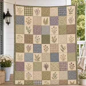 May include: A patchwork quilt featuring a grid of squares with botanical illustrations of wildflowers, ferns, and lavender, interspersed with solid-colored, plaid, and floral-patterned fabric blocks in shades of green, blue, and cream.