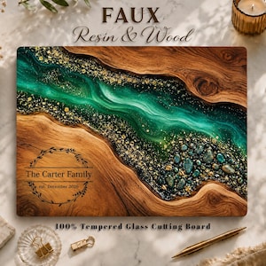 May include: A rectangular tempered glass cutting board featuring a natural wood grain pattern and a central river design made of emerald green resin with gold flecks. The board is engraved with a circular wreath and the text The Carter Family est. December 2026.