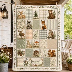 May include: A rectangular quilt featuring a grid of squares with illustrations of a deer, bear, raccoon, fox, moose, owl, rabbit, hedgehog, squirrel, and bird, interspersed with plaid, floral, and pine patterns, with the name Everett printed.