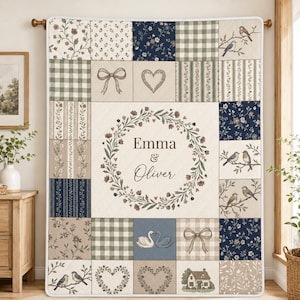 May include: A rectangular patchwork quilt featuring a central cream panel with a floral wreath surrounding the names Emma & Oliver. The surrounding squares display patterns of navy blue florals, green gingham, bows, hearts, birds on branches, and a house.