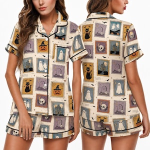 May include: A short-sleeve button-down pajama shirt and matching shorts set in a cream color featuring a repeating pattern of rectangular postage stamp illustrations depicting black cats, ghosts, pumpkins, skulls, tombstones, and haunted houses.