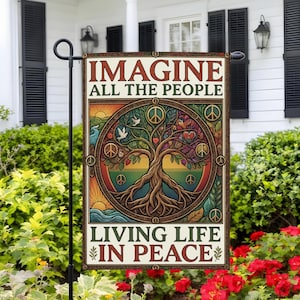 May include: A rectangular garden flag featuring the text IMAGINE ALL THE PEOPLE LIVING LIFE IN PEACE. The center displays a circular illustration of a tree with roots, peace signs, doves, and hearts in shades of green, brown, and orange.