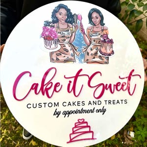 May include: White round sign with pink lettering that says "Cake it Sweet" and "Custom Cakes and Treats by appointment only". The sign features two cartoon women holding cakes and a pink and white cake illustration.