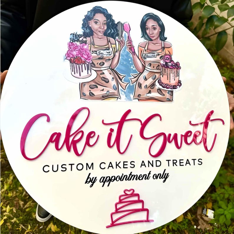 May include: White round sign with pink lettering that says "Cake it Sweet" and "Custom Cakes and Treats by appointment only". The sign features two cartoon women holding cakes and a pink and white cake illustration.