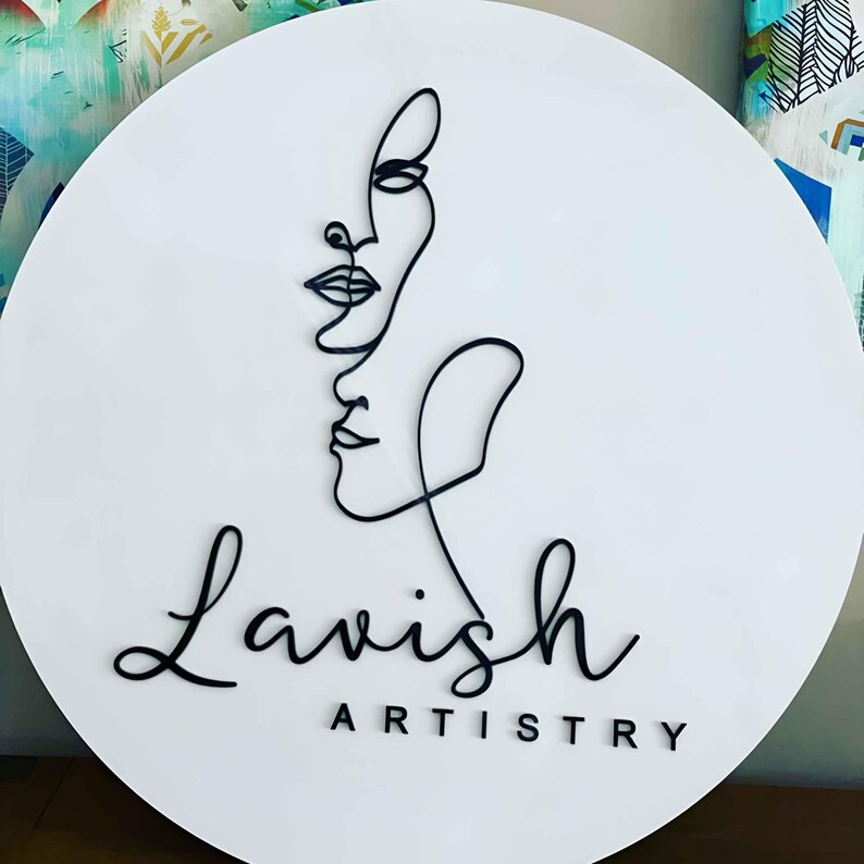 May include: A white circular sign with a black line drawing of two faces and the text "Lavish Artistry".