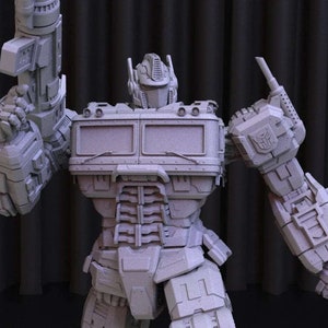 May include: A gray, detailed, robot toy in a robot mode. The robot has a large, rectangular chest with a detailed face and a large gun in its right hand.