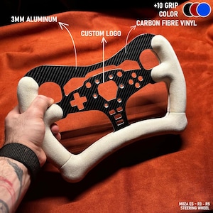 Puede incluir: Un volante negro y naranja con un diseño de fibra de carbono y empuñaduras blancas. El volante está hecho de aluminio de 3 mm y presenta un área de logotipo personalizada. El texto "+10 GRIP COLOR" y "CARBON FIBRE VINYL" son visibles. El modelo es MOZA ES - R3 - R5.