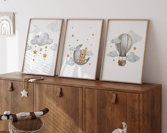 May include: Three framed watercolor prints with a nursery theme. The prints feature a teddy bear sitting on a crescent moon, a hot air balloon with clouds, and a cloud with stars and hanging stars.