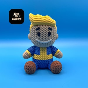 Może przedstawiać: Pluszowa zabawka postaci z żółtymi włosami, niebieskim kombinezonem i żółto-niebieskim wzorem. Zabawka siedzi na niebieskim tle.