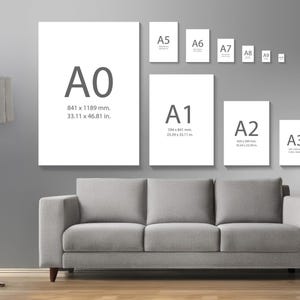 May include: A display of various paper sizes, including A0 (841 x 1189 mm, 33.11 x 46.81 in), A1, A2, A3, A4, A5, A6, A7, A8, and A9, against a gray wall. A gray sofa and a floor lamp are in the foreground. The sizes are labeled with dimensions.