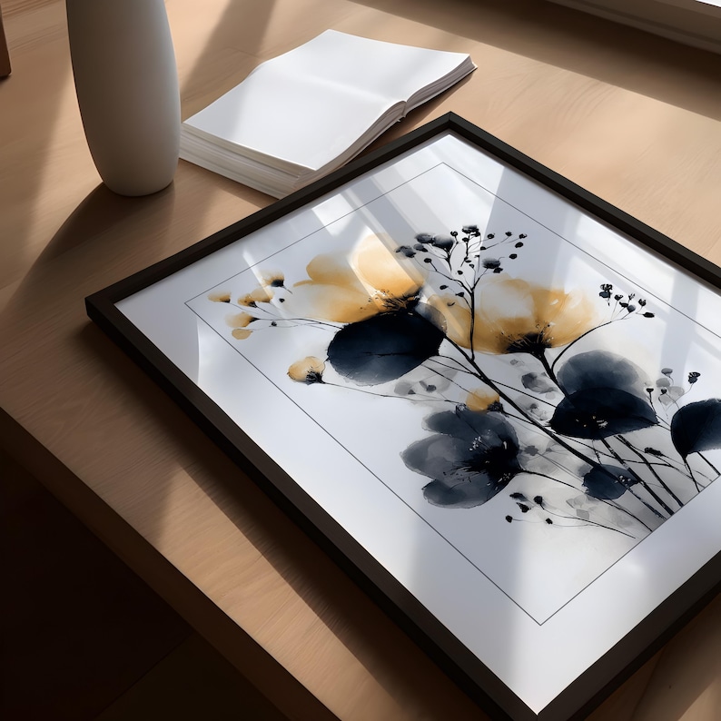 May include: A framed art print with a floral watercolour design in yellow and navy blue hues. The artwork is set against a white background and framed in a black frame. The print is displayed on a wooden surface.