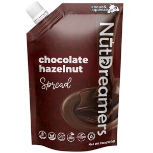 May include: A brown pouch with a white cap, labeled "NutDreamers" and "chocolate hazelnut Spread". The pouch has a red background with a pattern of hazelnuts. The pouch also has several certifications, including gluten-free, vegan, non-GMO, and palm oil free. The pouch is 12 ounces (340 grams).