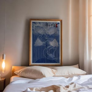 以下が含まれることがあります： 青と白の龍のデザインが描かれた額装されたプリントで、黒い文字と赤い文字で「千と千尋」と書かれています。プリントは白いベッドの2つの枕の上にかけられています。