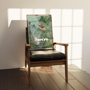 May include: A framed poster of the animated film "Ponyo" by Studio Ghibli, leaning against a black leather chair. The poster features a colorful illustration of a boat and the film's title in white. The chair has a wooden frame.