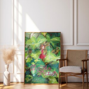 Pu&ograve; includere: Una locandina cinematografica incorniciata di Arrietty - Il mondo segreto sotto il pavimento con un piccolo personaggio in abito rosso tra grandi foglie verdi con gocce d'acqua. Il testo giapponese 借りぐらしのアリエッティ &egrave; stampato in rosa.