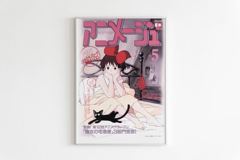 May include: Framed vintage Japanese anime magazine cover featuring a girl with a red bow, a black cat, and the text "Animage 5". The cover has a pink and gray color scheme.