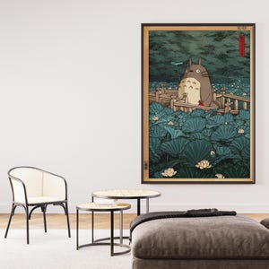 May include: Framed art print depicting a Totoro character in a tranquil, natural scene. The artwork shows a large, grey creature surrounded by vibrant, green lily pads and delicate white flowers, with a wooden bridge.