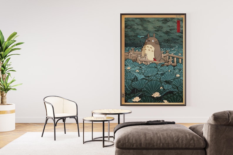 May include: Framed art print depicting a Totoro character in a tranquil, natural scene. The artwork shows a large, grey creature surrounded by vibrant, green lily pads and delicate white flowers, with a wooden bridge.
