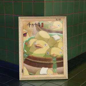 May include: A framed poster with a Japanese illustration of yellow ducklings in a wooden tub. The poster has the Japanese text "千と千尋" in red.