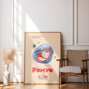 Puede incluir: Un p&oacute;ster enmarcado de la pel&iacute;cula de animaci&oacute;n "Ponyo". La obra de arte muestra un personaje dentro de una burbuja azul, con el t&iacute;tulo de la pel&iacute;cula en rojo. El p&oacute;ster se exhibe en una habitaci&oacute;n con suelo de madera y una silla.
